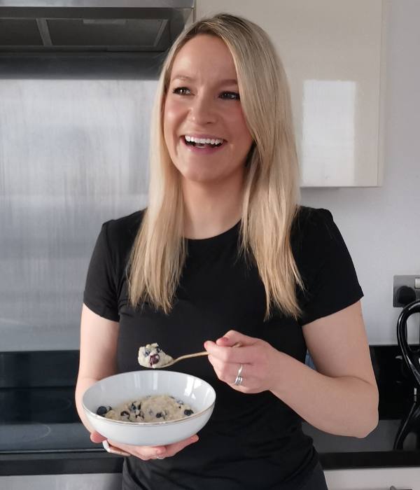 Amy smiling in the kitchen holding a bowl of porridge
